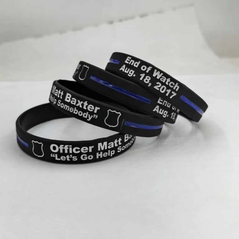 Black custom silicone memorial wristbands with white lettering, shield motif and blue stripe