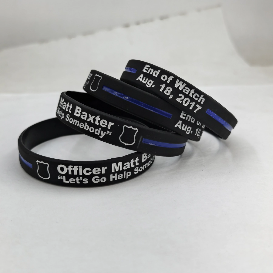 Black custom silicone memorial wristbands with white lettering, shield motif and blue stripe